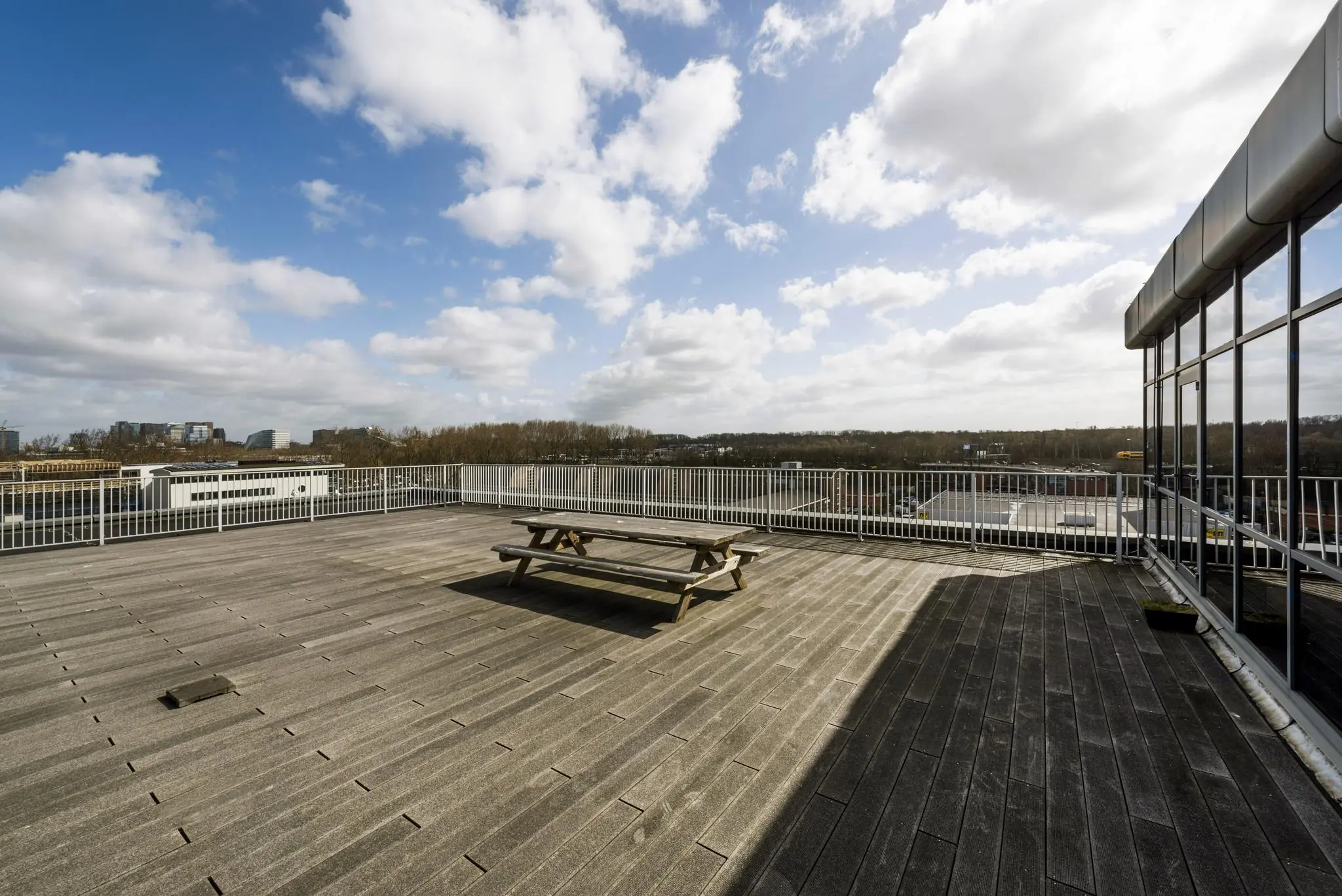 Dakterras met houten picknicktafel en uitzicht op bedrijventerrein aan de Anthony Fokkerweg.